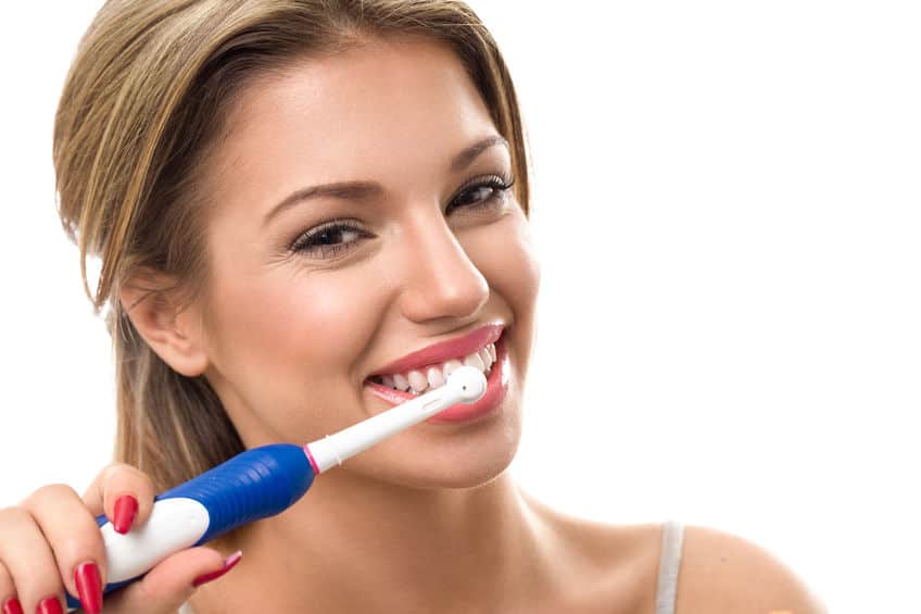 young beautiful woman brushing her healthy teeth with best electric toothbrush